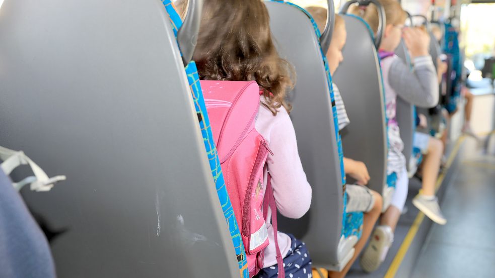 Kinder sitzen mit ihrem Ranzen in einem Schulbus. Foto: DPA