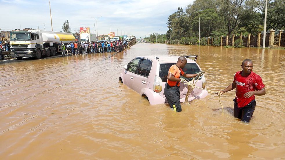 Menschen in Nairobi, die im Hochwasser ein Auto ziehen. Foto: Joy Nabukewa/XinHua/dpa