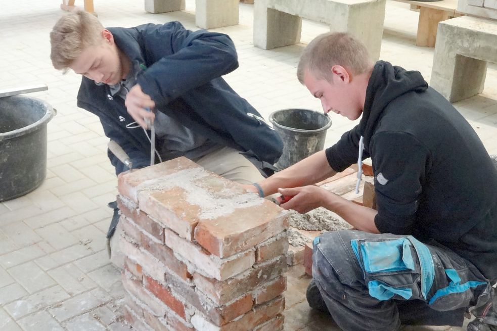 Sven Rieken (links), 21 Jahre, aus Westerende-Kirchloog, und der 20-jährige Markus Biller aus Veenhusen mauern mit Kalkknotelmörtel und historischen Steinen an einem Widerlager für einen geplanten Bogen. Foto: Monumentendienst