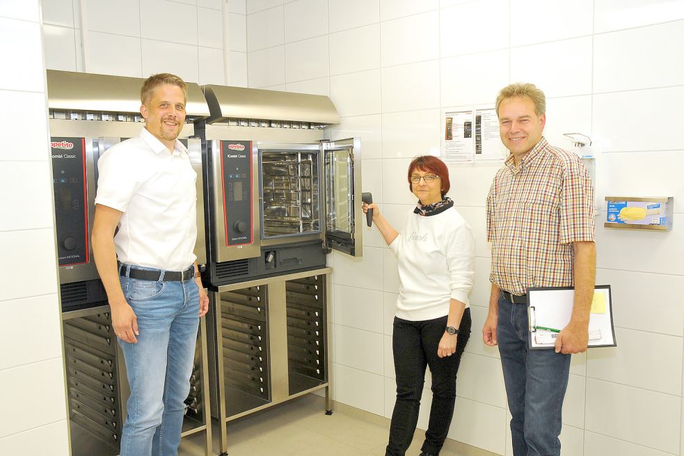 Frank Cramer (von links), Susanne Schoof und Ralf Biller zeigen die beiden neuen Dampfgarer der Ausgabeküche. Foto: Gemeinde Großefehn