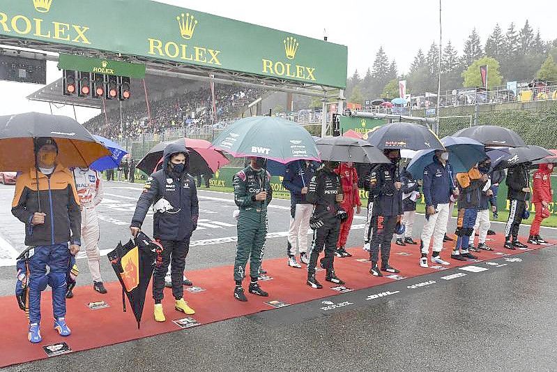 Die Fahrer stehen vor dem Start zusammen im Regen. Foto: John Thys/Pool AFP/AP/dpa