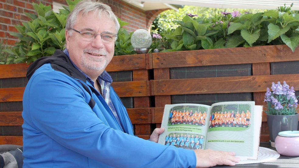 Reinhard de Groot, Trainer der Ü60 SG Plaggenburg, hält einen Bildband mit vielen Fotos in der Hand. Gut zu erkennen sind die orangegefärbten Trikots der SG-Oldies. Foto: Wolf-Rüdiger Saathoff