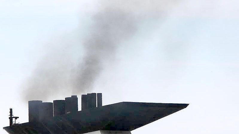 Eine dunkle Abgaswolke steigt aus dem Schornstein eines Fährschiffs bei der Ausfahrt aus dem Seehafen. Foto: Jens Büttner/dpa-Zentralbild/dpa