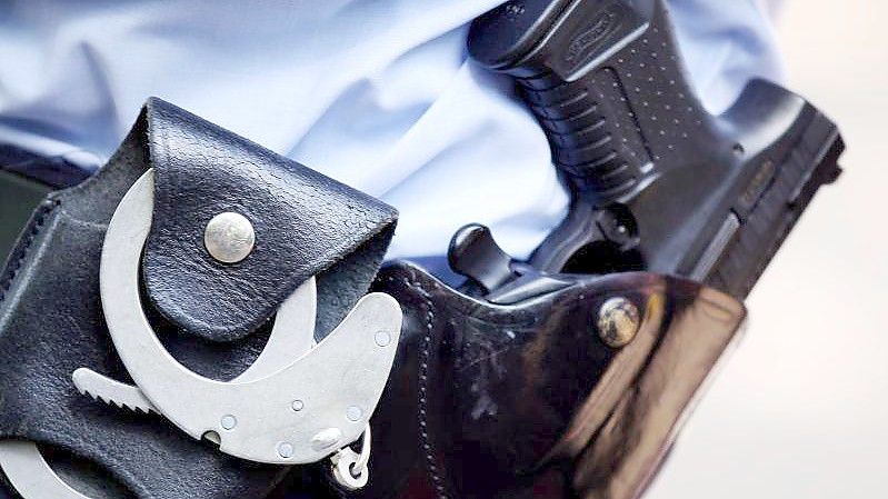 Ein Polizist mit Handschellen und Pistole am Gürtel. Symbolbild. Foto: picture alliance / dpa