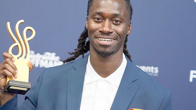 Der Schauspieler Eugene Boateng zeigt seinen Preis. Foto: Jörg Carstensen/dpa