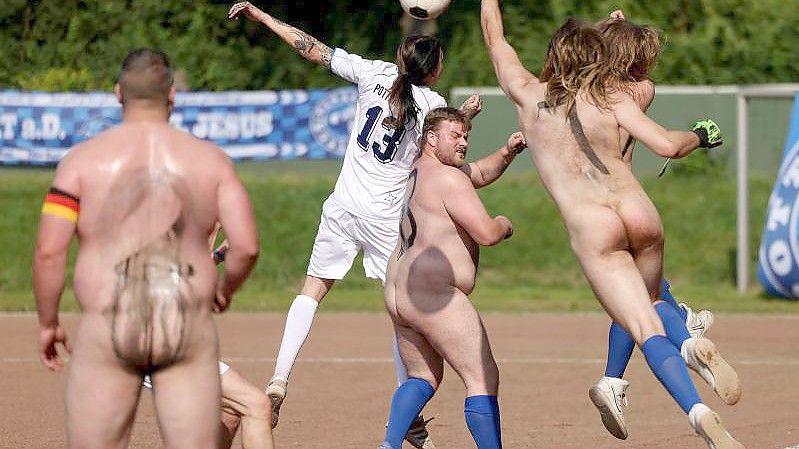 Spieler der Fußball-NACKTionalmannschaft kämpfen ohne Trikots gegen das Team der Pottoriginale (weiße Trikots) um den Ball. Foto: Oliver Berg/dpa