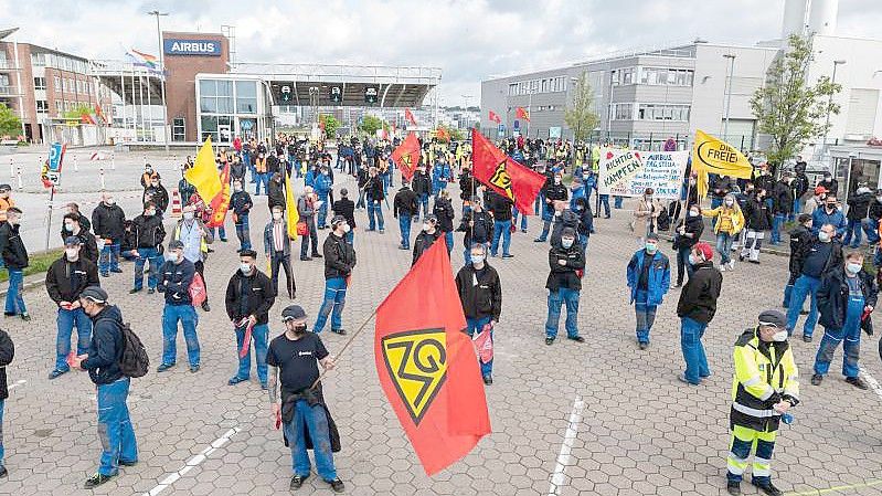 Airbus-Beschäftigte in Hamburg-Finkenwerder demonstrieren im Mai 2021 vor den Toren des Werksgeländes. Die Verhandlungen zwischen Airbus und der IG Metall über den seit Monaten umstrittenen Konzernumbau gehen in die zweite Runde. Foto: Daniel Reinhardt/dpa