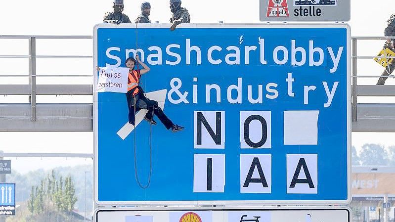 Ein Aktivist bei einer Banneraktion an einer Schilderbrücke über der Autobahn A9 bei Fürholzen in Fahrtrichtung München. Foto: Matthias Balk/dpa