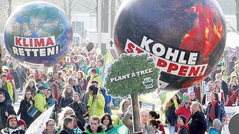 Demonstranten fordern in Bonn mit einem Modell der Erdkugel mit der Aufschrift "Klima retten" und einer weiteren mit der Aufschrift "Kohle stoppen" die Umsetzung des Weltklimaabkommens. Foto: picture alliance / Roland Weihrauch/dpa