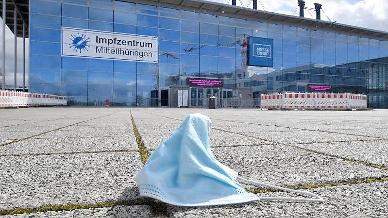 Eine Maske liegt vor dem Impfzentrum in der Messe Erfurt. In den ostdeutschen Bundesländern sind weniger Menschen gegen Covid-19 geimpft als bundesweit. Foto: Martin Schutt/dpa-Zentralbild/dpa