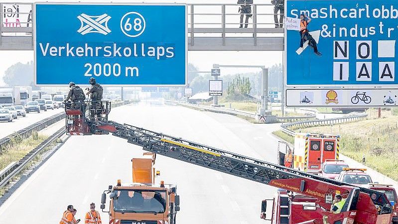 Ein Aktivist hängt während einer Banneraktion an einer Schilderbrücke über der Autobahn A9 bei Fürholzen in Fahrtrichtung München. Foto: Matthias Balk/dpa