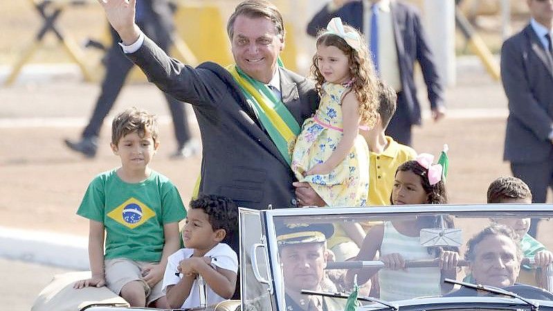Jair Bolsonaro (M) kommt zu einer Flaggenhissungszeremonie in der Präsidentenresidenz. Foto: Eraldo Peres/AP/dpa