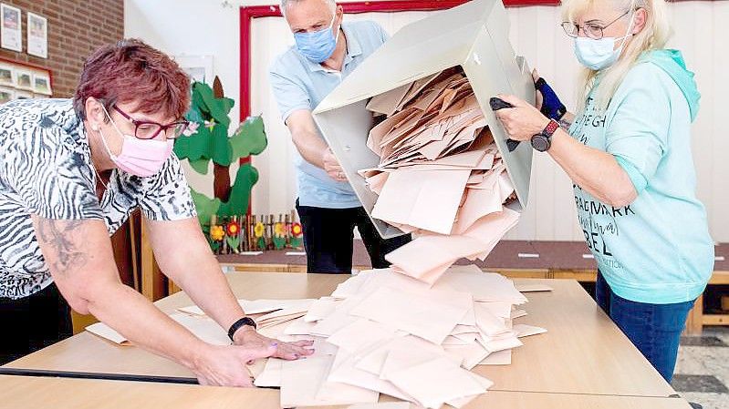 Wahlhelferinnen und ein Wahlhelfer entleeren im niedersächsischen Delmenhorst eine Wahlurne mit Stimmzetteln. Foto: Hauke-Christian Dittrich/dpa