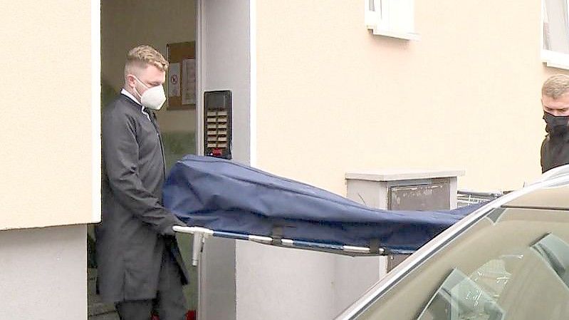 Bestatter bringen das Opfer zu ihrem Fahrzeug. Foto: TNN/dpa