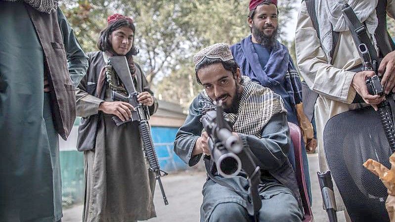 Ein junger Taliban-Kämpfer zielt zum Spaß mit seinem Gewehr in Richtung Fotograf, während er vor einer Polizeistation in Kabul Wache hält. Foto: Oliver Weiken/dpa