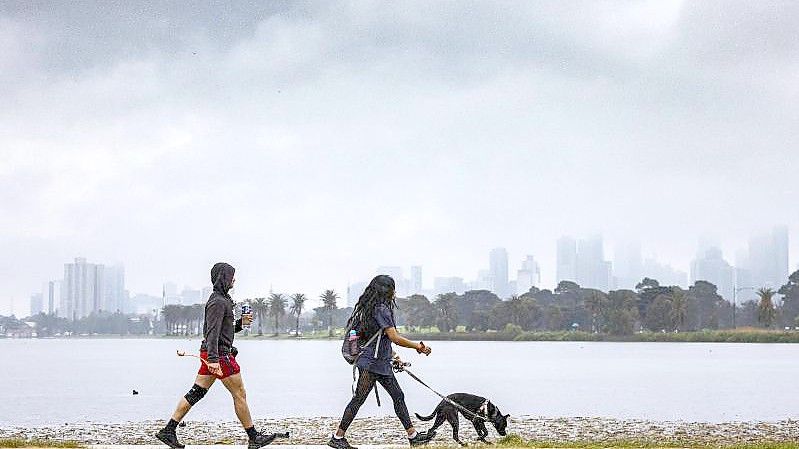 Menschen gehen mit einem Hund am Albert Park Lake in Melbourne spazieren. (Archivbild). Foto: Daniel Pockett/AAP/dpa