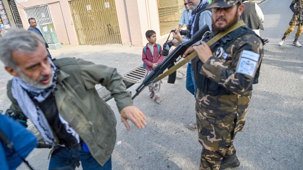 Sicherheitskräfte der Taliban verscheuchen einen Journalisten, der über Frauenprotest vor einer Schule in Kabul berichten will. Gegner des Regimes leben gefährlich. Foto: Bulent Kilic/AFP