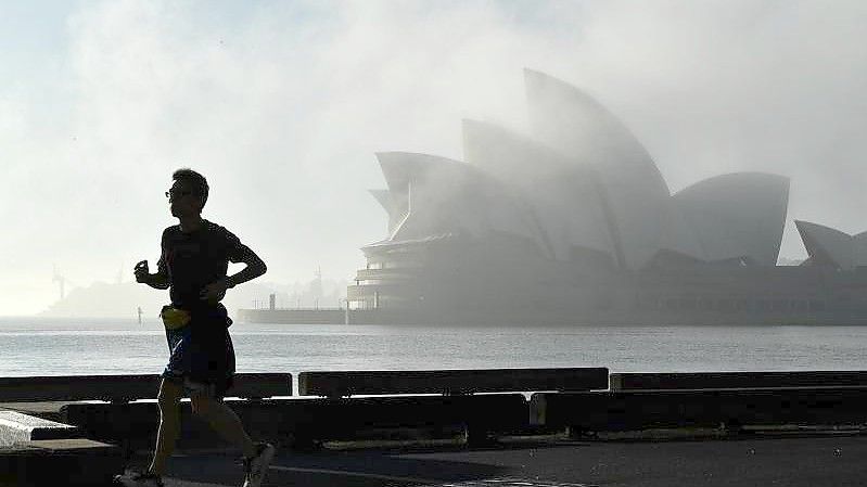 Morgennebel über dem Opernhaus in Sydney. Unentschlossene Bewohner Australiens sollen jetzt mit Hilfe einer Millionen-Lotterie dazu bewegt werden, sich gegen das Coronavirus impfen zu lassen. Foto: Joel Carrett/AAP/dpa