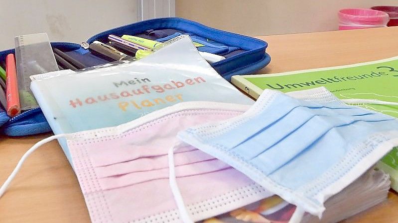 Masken liegen während einer Pause auf Arbeitsmaterialien eines Schülers in einem Klassenraum einer Grundschule. Foto: Patrick Pleul/dpa-Zentralbild/dpa