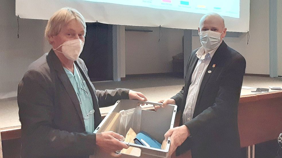 Bernhard Onnen (links) brachte die Box mit den Ergebnissen aus Felde ins Bürgerhaus, wo Bürgermeister Erwin Adams sie in Empfang nahm. Foto: Karin Böhmer
