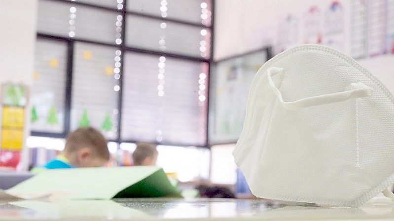 Eine FFP2-Maske liegt in einer Grundschule auf einem Tisch. In zwei Bundesländern greifen ab Montag Lockerungen bei der Maskenpflicht an Schulen. Foto: Sebastian Gollnow/dpa