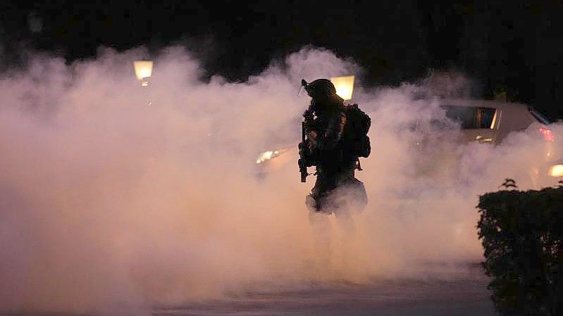 Ein Polizist geht durch Rauch während einer Demonstration gegen Corona-Impfungen in Ljubljana. Foto: Petr David Josek/AP/dpa