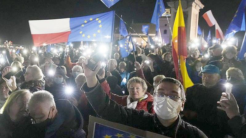 Menschen halten während einer Demonstration in Warschau die Taschenlampen ihrer Mobiltelefone hoch. Foto: Czarek Sokolowski/AP/dpa