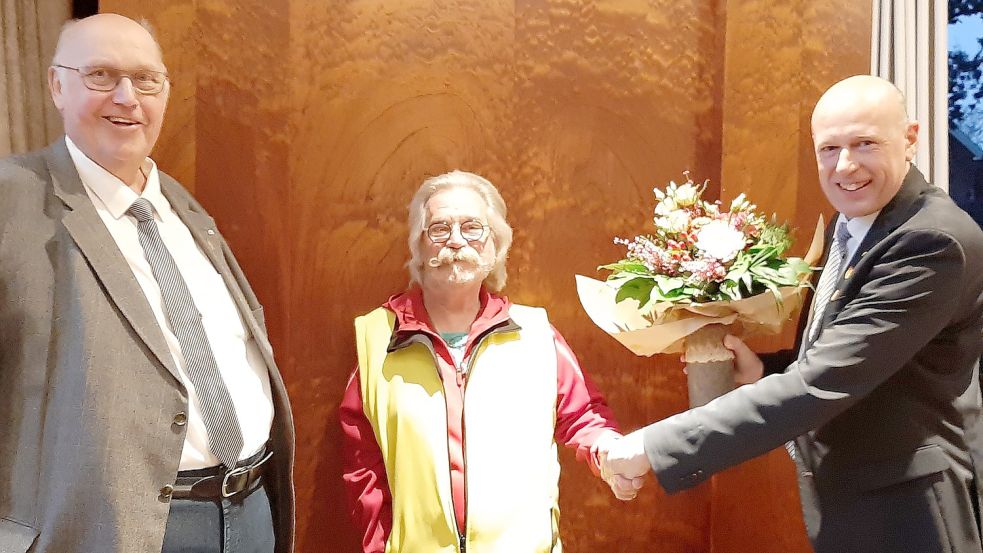 Mit einem Blumenstrauß bedankten sich der Ratsvorsitzende Onno Reents (links) und Bürgermeister Erwin Adams (rechts) bei Karl Reuter. Foto: Ann-Kathrin Stapf