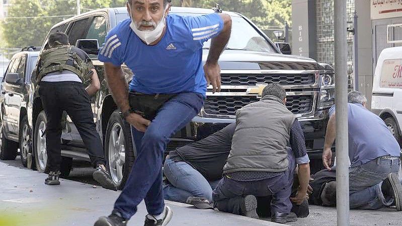 Schüsse der Sicherheitskräfte: Personen gehen hinter einem Auto in Deckung und versorgen einen verletzten Mann. Foto: Hassan Ammar/AP/dpa