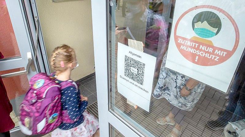 Ein Kind geht mit Maske in eine Schule. Das Robert Koch-Institut (RKI) registriert in einzelnen Regionen Deutschlands besonders viele Corona-Ansteckungen bei Kindern und Jugendlichen. Foto: Jens Büttner/dpa-Zentralbild/dpa