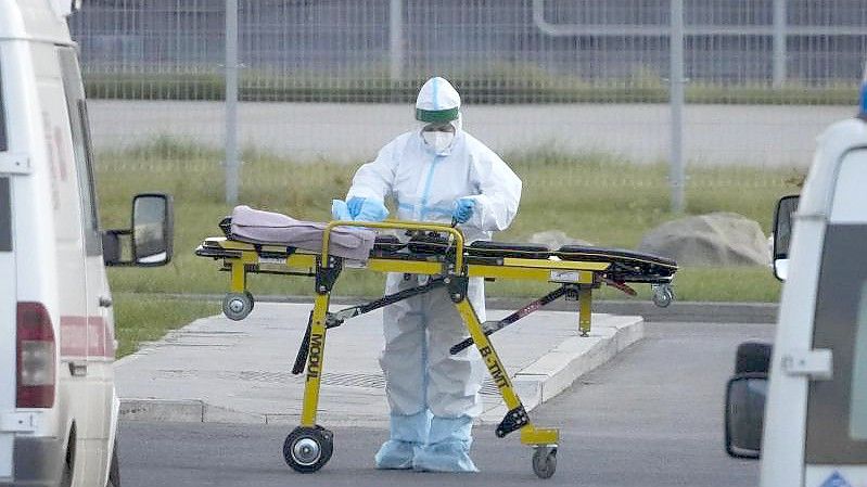 Ein medizinischer Mitarbeiter bereitet eine Trage vor einem Krankenhaus in Kommunarka vor. Foto: Alexander Zemlianichenko/AP/dpa