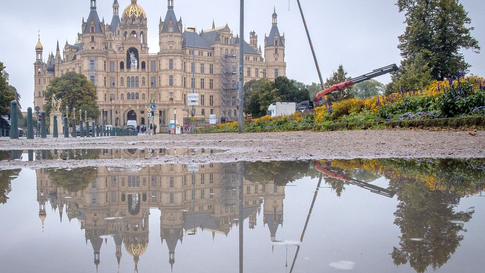 27.09.2021, Mecklenburg-Vorpommern, Schwerin: Der Landtagssitz im Schweriner Schloss spiegelt sich in einer Pfütze. Die Parteien im Nordosten beraten über das Ergebnis der Landtagswahlen vom 26.09.2021. Foto: Jens Büttner/dpa-Zentralbild/dpa +++ dpa-Bildfunk +++ Foto: Jens Büttner/dpa
