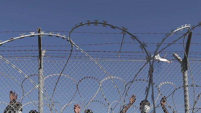 Migranten stehen hinter einem Zaun in einem Flüchtlingslager in Kokkinotrimithia außerhalb Zyperns Hauptstadt Nikosia. Foto: Petros Karadjias/AP/dpa