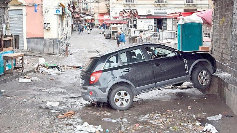 Ein Auto steckt, einen Tag nachdem Sizilien von einem heftigen Unwetter mit Überschwemmungen heimgesucht wurde, unter einer Unterführung an einer Mauer fest. Foto: Andrea Di Grazia/LaPresse/AP/dpa