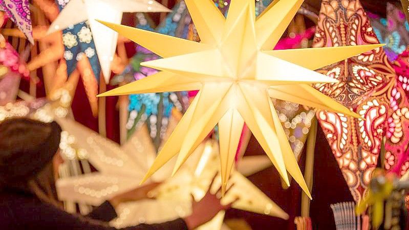 Bunte Weihnachtssterne werden an einem Stand auf dem Weihnachtsmarkt angeboten. Foto: Friso Gentsch/dpa