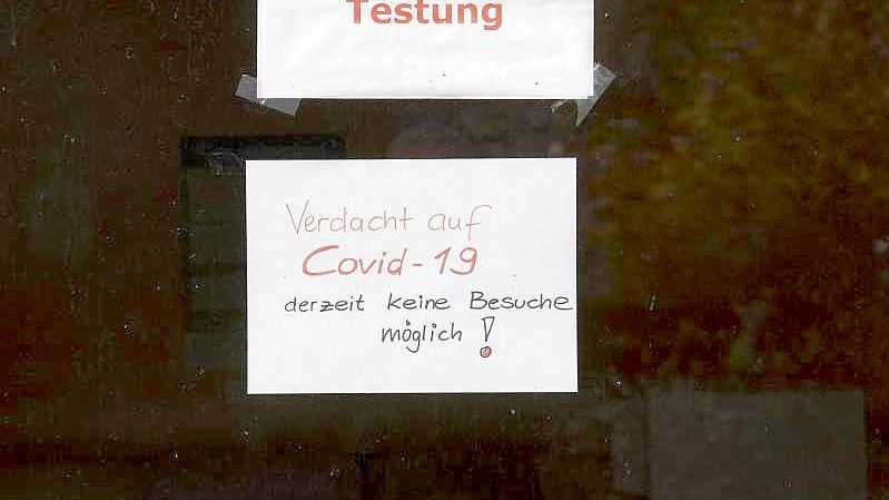 "Warteraum Testung" und "Verdacht auf Covid-19 derzeit keine Besuche möglich!" steht auf Zetteln an einer Scheibe in dem Seniorenheim, in dem es zum Corona-Ausbruch gekommen ist. Foto: Paul Zinken/dpa