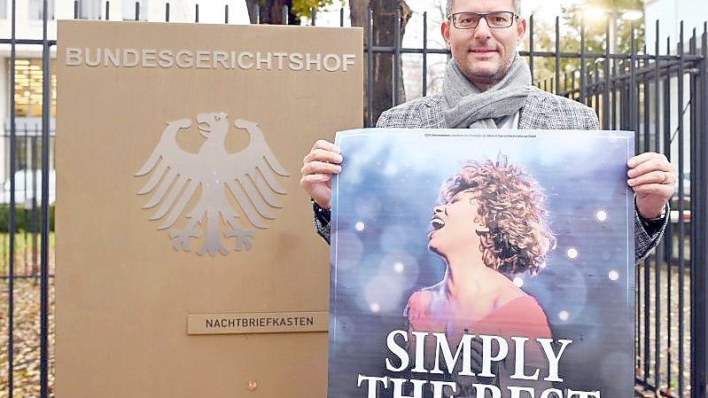 Tourneeveranstalter Oliver Forster vor dem Bundesgerichtshof (BGH) mit Plakat der Show „Simply The Best - Die Tina Turner Story“. Foto: Uli Deck/dpa