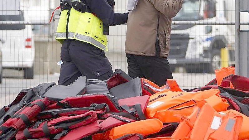 Ein Flüchtling wird von Beamten der Grenzpolizei nach Dover in Kent gebracht. Foto: Gareth Fuller/PA/dpa