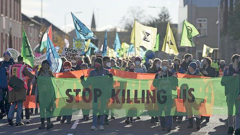 Aktivisten der Umweltschutz-Organisation Extinction Rebellion tragen bei einer Demonstration parallel zum Weltklimagipfel COP26 ein Transparent mit der Aufschrift „Stop Killing Us“ (Hört auf, uns zu töten). Foto: Alastair Grant/AP/dpa