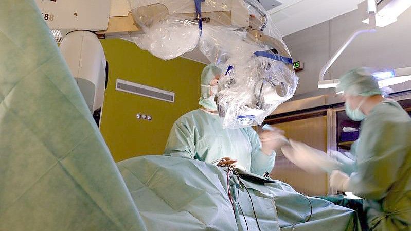Ein Mediziner operiert in einer Klinik in Baden-Württemberg während einer Bandscheibenoperation an der Lendenwirbelsäule mit einem Mikroskop. Foto: Felix Kästle/dpa