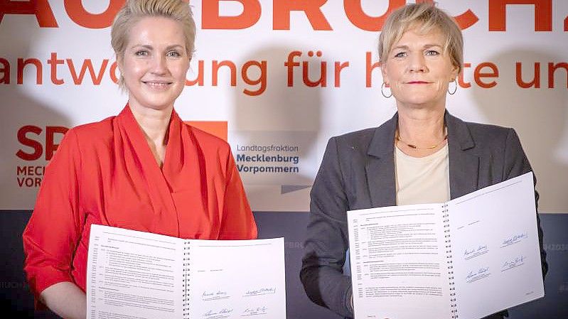 Manuela Schwesig (SPD, l), die Ministerpräsidentin von Mecklenburg-Vorpommern, und Simone Oldenburg (r), die Fraktionschefin der Linken im Landtag von Mecklenburg-Vorpommern, zeigen den unterzeichneten Koalitionsvertrag zwischen SPD und der Linken für eine gemeinsame Regierungsbildung in Mecklenburg-Vorpommern. Foto: Jens Büttner/dpa-Zentralbild/dpa