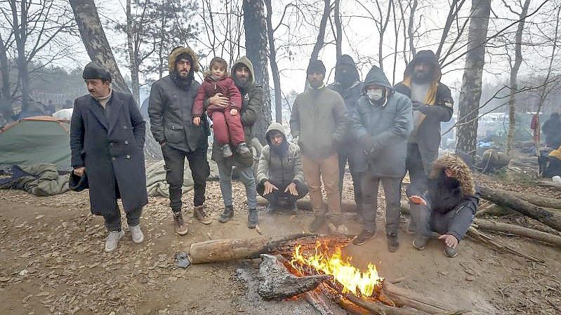 Migranten versammeln sich an der belarussisch-polnischen Grenze an einem Feuer, um sich zu wärmen. (Archivbild). Foto: Ramil Nasibulin/BelTA/AP/dpa