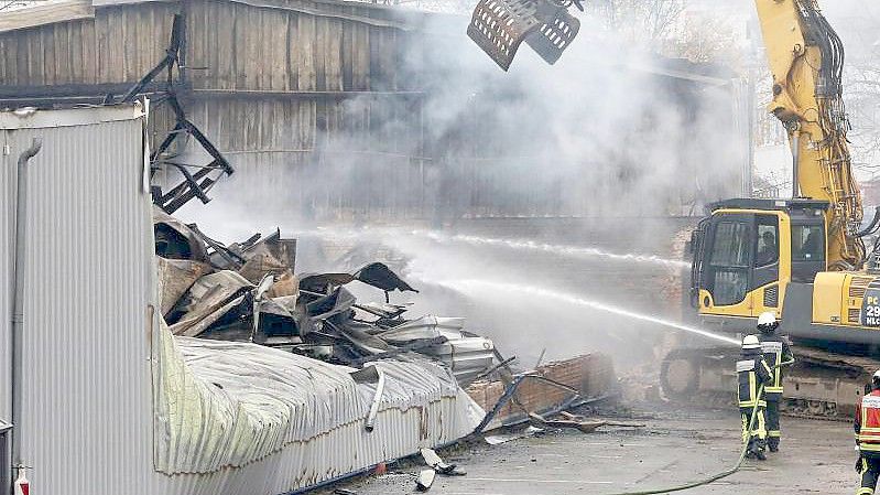 Mit einem Abrissbagger sucht die Feuerwehr nach letzten Brandnestern. Foto: Roland Weihrauch/dpa