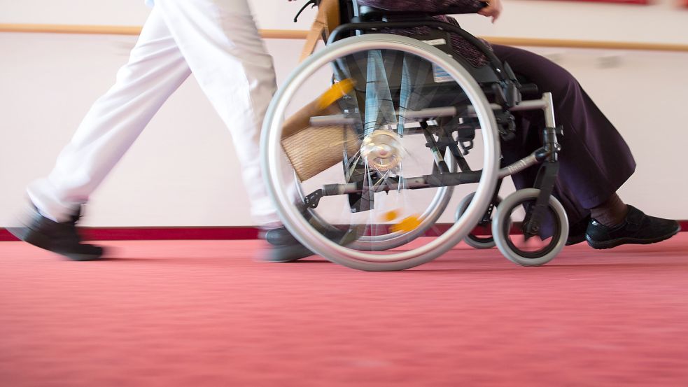 Ein Pfleger eines Pflegeheims schiebt eine Bewohnerin in einem Rollstuhl. Die Bezahlung in der Pflege hat sich trotz hoher Belastungen zuletzt nicht wesentlich verbessert, wie die Linksfraktion im Bundestag beklagt. Foto: Tom Weller/dpa
