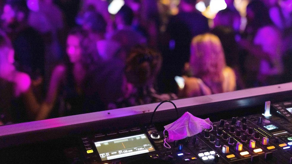 Tanzende vor einem DJ-Pult. Foto: DPA