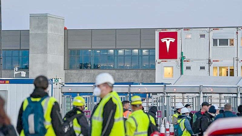Arbeiter warten am frühen Morgen an einem Eingang zur Baustelle für die Tesla-Autofabrik. Foto: Patrick Pleul/dpa-Zentralbild/dpa