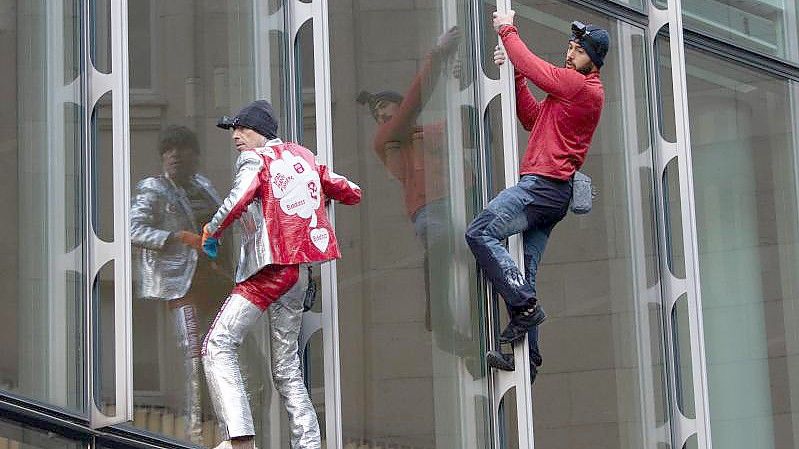 Die beiden Extremkletterer Leo Urban (r) und Alain Robert kletterten ohne jede Sicherung an der Fassade des Skyper-Hochhauses in Frankfurt am Main hinauf. Foto: Boris Roessler/dpa