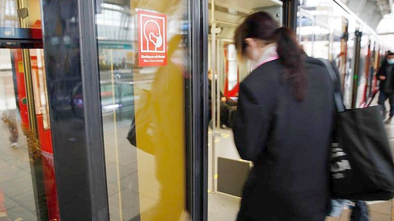 Rote Schilder weisen auf der S-Bahn Tür auf die Pflicht zum Tragen einer Maske hin. Foto: Carsten Koall/dpa