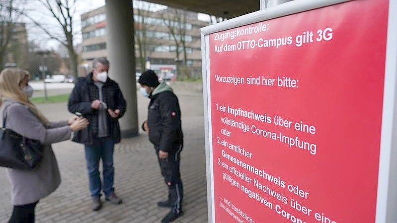 Mitarbeiter werden am Eingang des Otto-Campus der Otto Group gemäß den 3G-Regeln von Sicherheitsmitarbeitern kontrolliert. Foto: Marcus Brandt/dpa