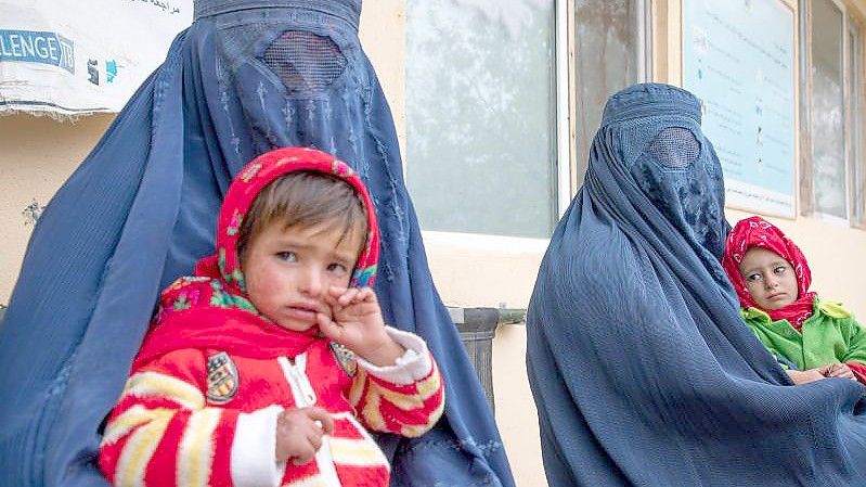 Zwei afghanische Frauen warten mit ihren Kindern vor einer Klinik für Ernährungsfragen. Foto: Julian Frank/WFP/dpa